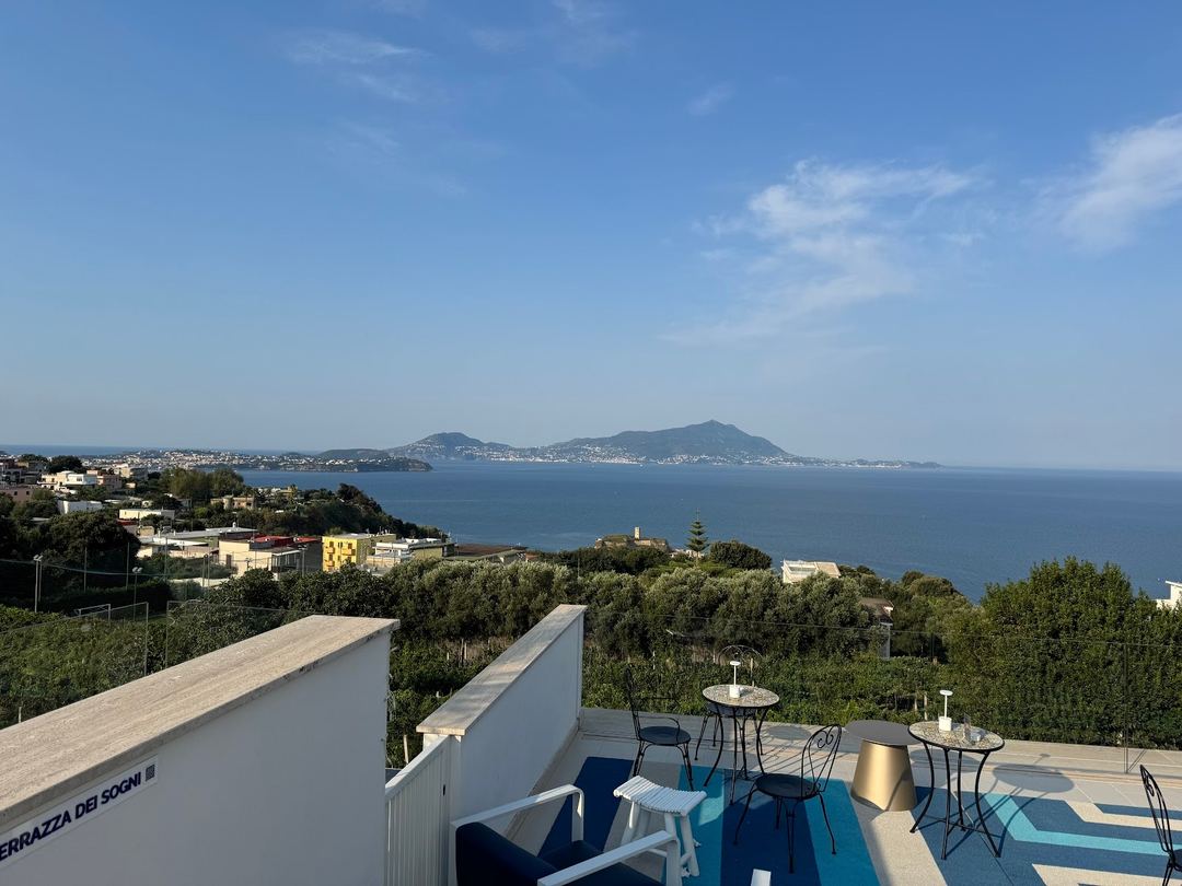 Panoramic coastal view from the hotel's terrace overlooking the Bay of Naples with Mount Vesuvius visible in the distance.